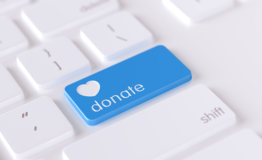 Donation  icon written on a blue button of a computer keyboard. Horizontal composition with selective focus and copy space. High angle view. Charity concept.