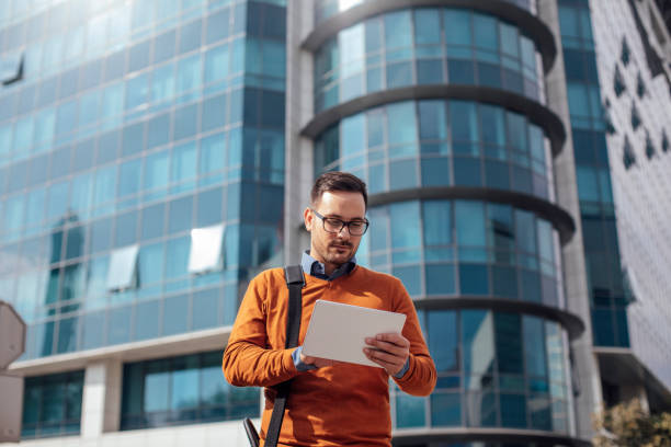 Successful Modern Young Businessman Using a Digital Tablet on the Street
