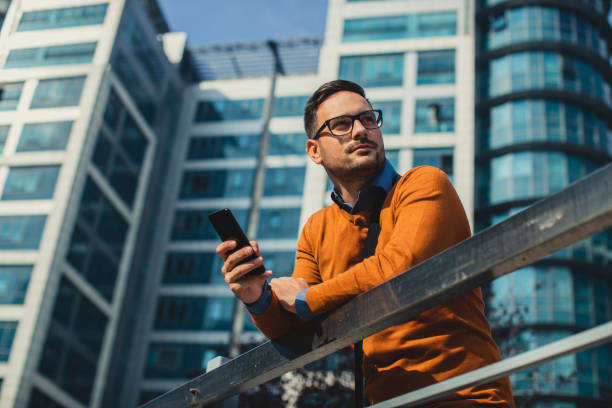 Confident Young Businessman Using his Smartphone in front of an Office Building