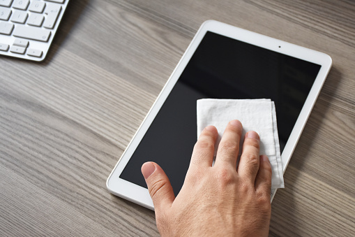 Man hands cleaning disinfection digital tablet on the desk