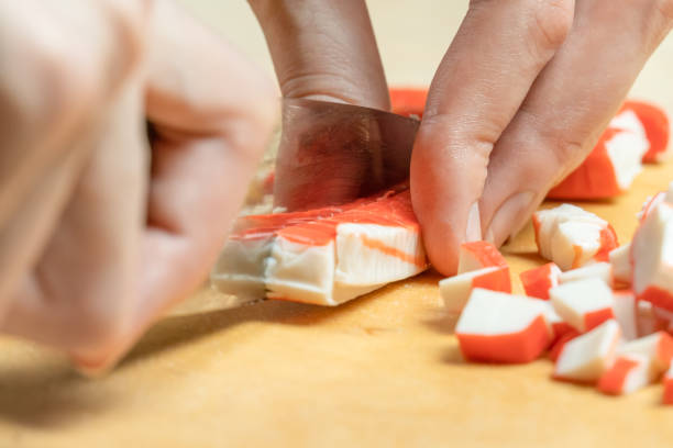 istock Women's hands cut crab sticks on a wooden board close up 1223065490