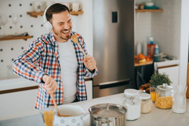 istock Attractive young man dancing and singing in the kitchen stock photo 1223065951