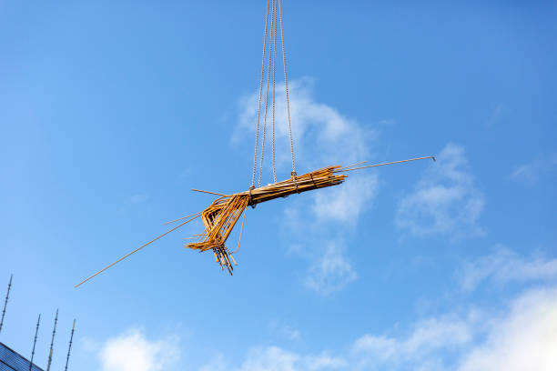 Tower crane lifting steel rods, blue sky background with copy space, full frame horizontal composition