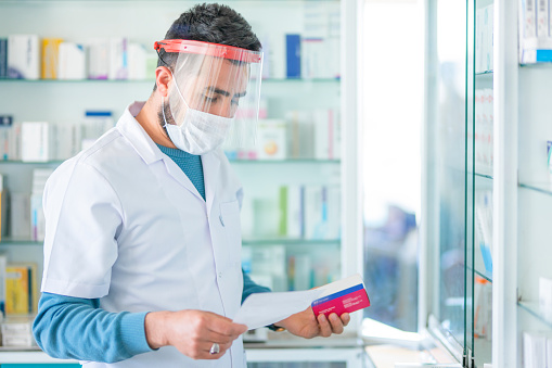 Pharmacist wears protective mask at work gives prescription medicine