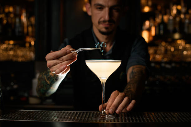 istock Male bartender decorates alcohol drink with small flower 1223077264