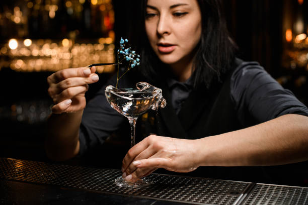 istock Female bartender decorates alcohol cocktail with small flower 1223078477