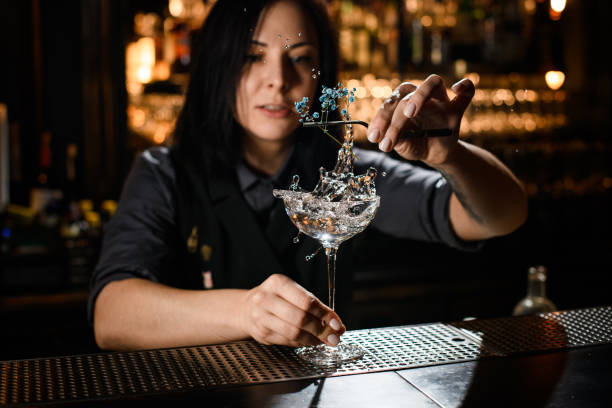 istock Female bartender decorates alcohol drink with small flower 1223078515