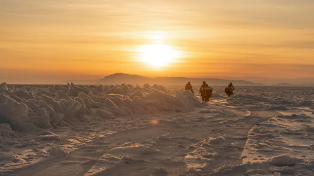 bicyclists crossing baikal lake in winter on the sunset, russia - weather time travel locations nature imagens e fotografias de stock