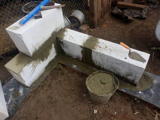 istock Bricklayer builder laying autoclaved aerated concrete blocks, aac on house foundation wall 1223083229