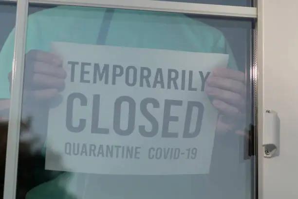 TEMPORARILY CLOSED sign on a frontdoor, Close Up. Restaurant closed due to the Coronavirus. Sticker labeled TEMPORARILY CLOSED.