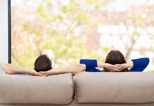 istock couple relaxing on a sofa at home and looking outside 1223089040