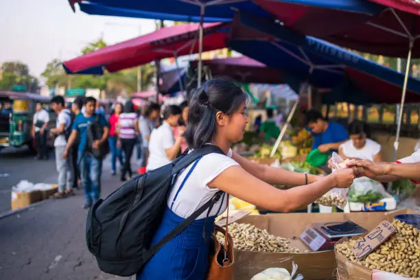 Young Asian woman buying food at street food stall