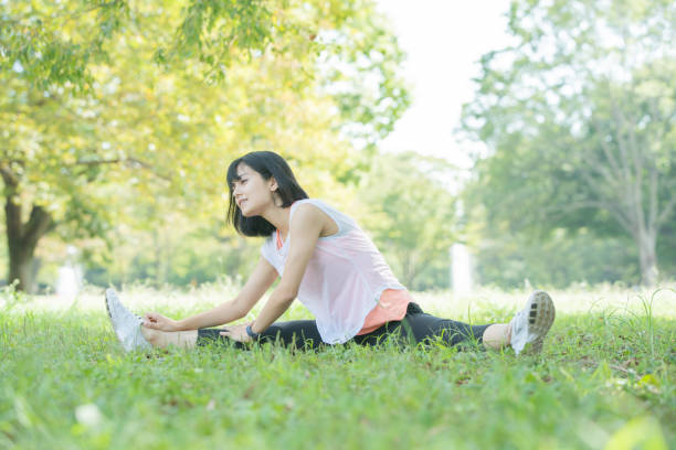 stretching in the park Asian (Japanese) young woman stretching in a park full of greenery forest bathing photos stock pictures, royalty-free photos & images