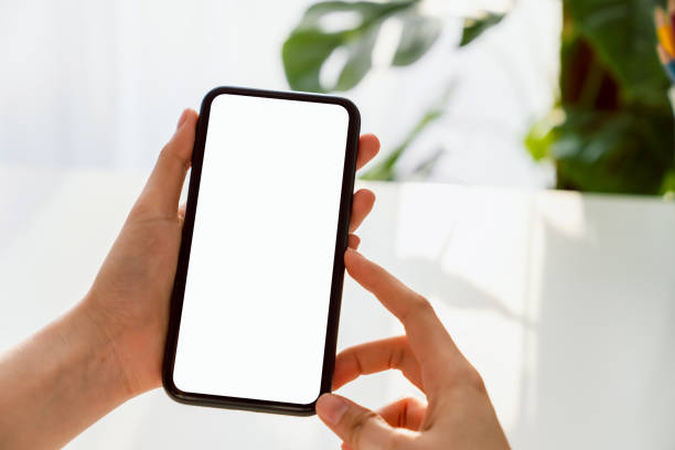 istock Hand holding smartphone mockup of blank screen on the table. Take your screen to put on advertising. 1223105341