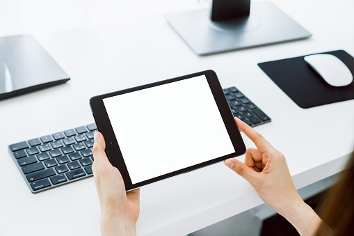 Woman holding digital tablet mockup of blank screen and computer on the table office. Take your screen to put on advertising.