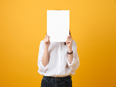 Young woman holding blank paper on the yellow background. for advertising signs.