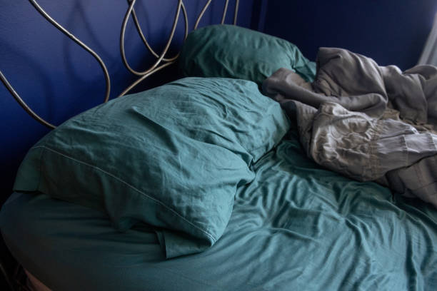 istock Pillows in Messy Unmade Bed Indoors During Coronavirus Stay at Home Order 1223107717