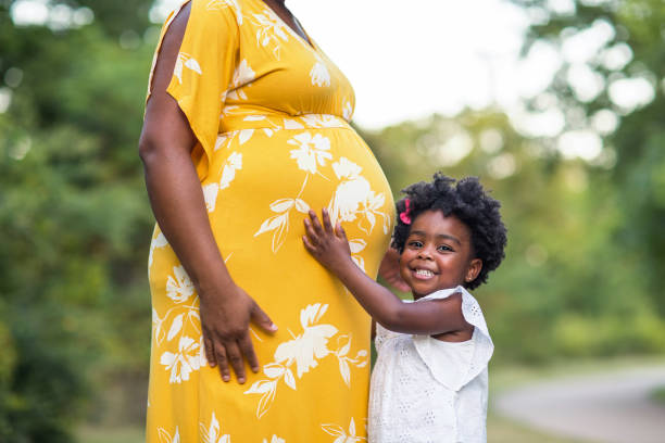 Portrait of a beautiful African American Pregnant Woman Young pregnant woman holding her stomach smiling. dress photos stock pictures, royalty-free photos & images