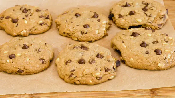 Photo of Chocolate Chip Cookies with pine nuts close up on wooden background. Homemade old-fashioned Chocolate Chip Cookies. American cuisine, dessert