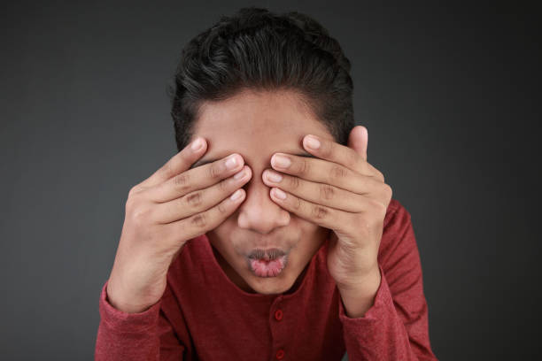 istock Young boy blocks his eyes with hands 1223131584