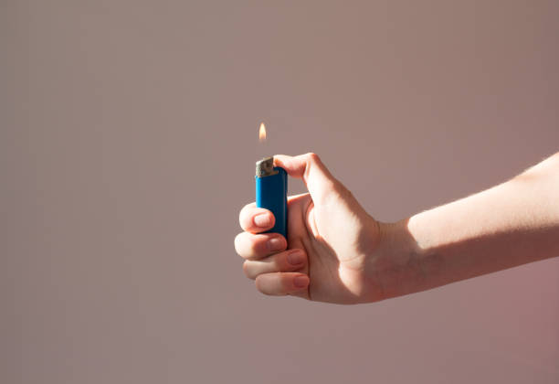 lżejsze oparzenia w dłoni w cieniu. mężczyzna trzyma zapalniczkę z płomieniem. koncepcja ognia i palenia - tobacco sticks zdjęcia i obrazy z banku zdjęć