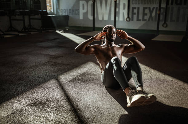 Sweaty black athlete doing sit-ups in a gym.