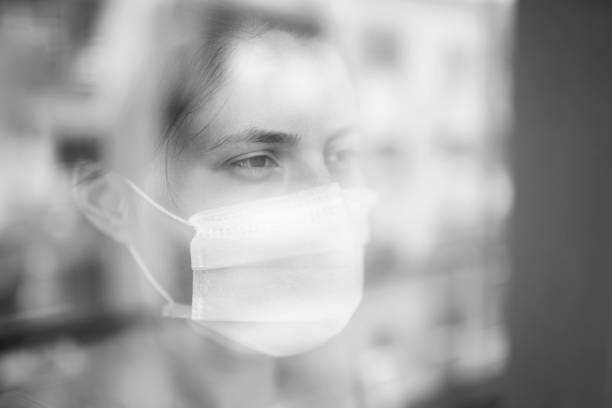 istock Young woman in quarantine looking through the window 1223135549