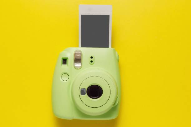 현대 녹색 폴라로이드 카메라, 노란색 배경에 사진. 상단보기, 부드러운 최소한의 플랫 레이 스타일 구성. 관광 개념. 텍스트에 대한 복사 공간 - shot glass flash 뉴스 사진 이미지