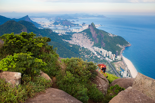 Single female mountain climber above Rio De Janeiro Brazil leaping between rocks
