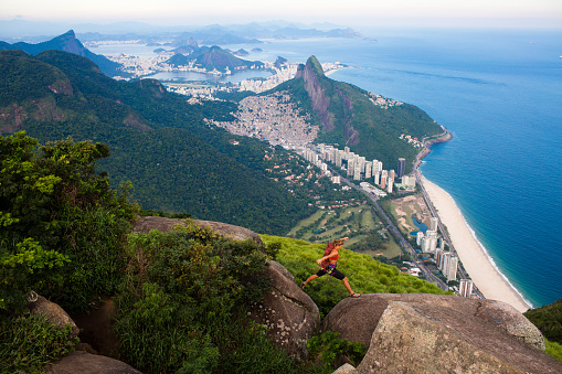 Single female mountain climber above Rio De Janeiro Brazil leaping between rocks