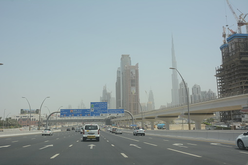 Dubai, UAE - August 20, 2016: The view of the street in Dubai, UAE during the day with towers and Burj Khalifa building on the background