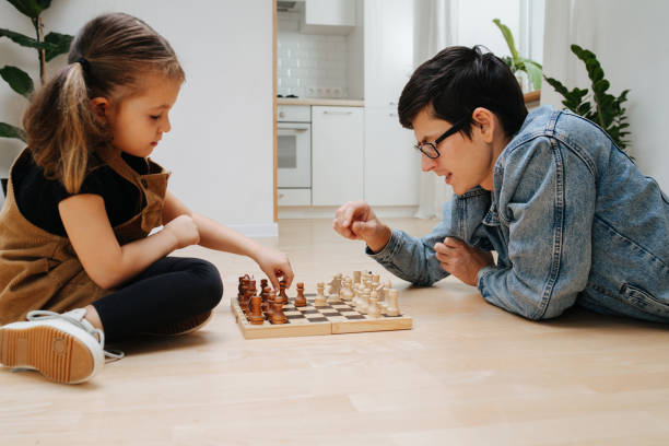 istock Chess. Father thinks on a counter move against little daughter on kitchen floor 1223137205