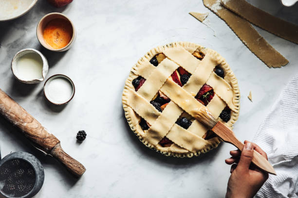 Woman brushing a typical fruit lattice pie Woman working on a tasty sweet german lattice pie savory food photos stock pictures, royalty-free photos & images