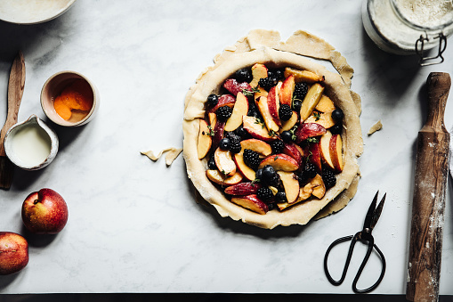 Directly above photograph of a nectarine, blueberry and blackberry lattice fruit pie with a little bit of cognac