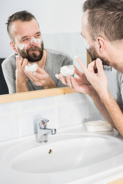 istock Man applying moisturizer cream in bathroom 1223139287