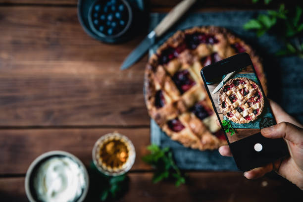 young woman taking a photo of her fresh fruit lattice pie - blueberry fruit berry berry fruit imagens e fotografias de stock