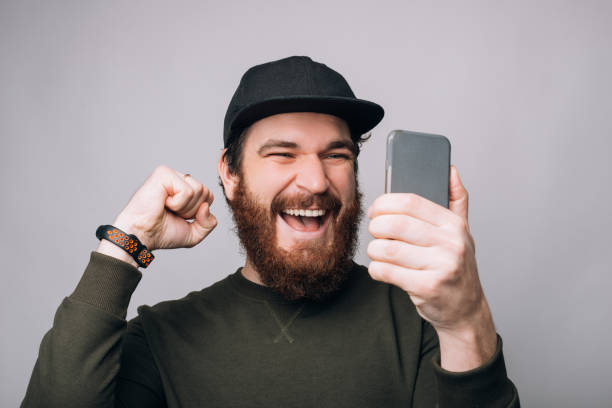 istock Excited man looking at his phone is making winner gesture on white background. 1223139360