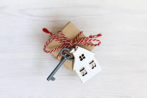 house with key and gift top view on a light wooden surface
