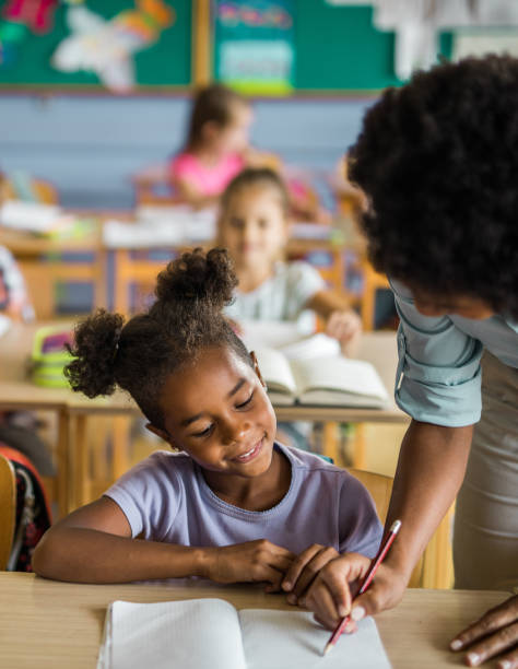 istock Happy black girl having teacher's assistance during a class at elementary school. 1223141282