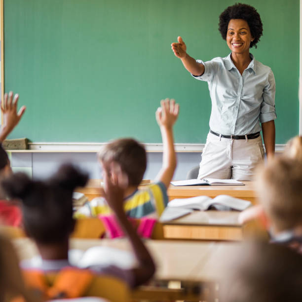 istock Happy African American elementary teacher aiming at school kid to answer her question. 1223144130