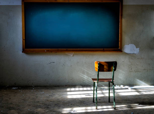 aula abbandonata con sedia davanti alla lavagna vintage - blackboard desk classroom education foto e immagini stock