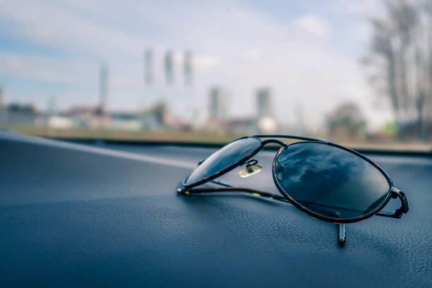 istock Black eyeglasses on black textured car dashboard in selective focus against blur background 1223146740