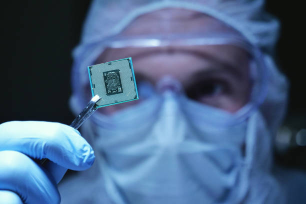 in ultra modern electronic manufacturing factory design engineer in sterile coverall holds microchip with symbols in futuristic holography. - computer chip imagens e fotografias de stock