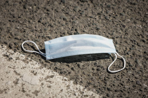 Protective medical mask thrown on the road stock photo