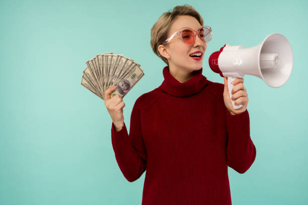 mujer joven con gafas de sol rosas con dinero gritando al altavoz - easy money audio fotografías e imágenes de stock