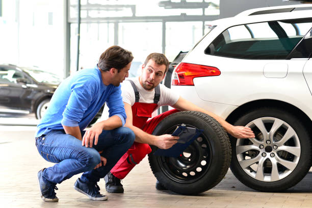 service à la clientèle dans un garage - mécanicien et client discutent de la réparation d’un véhicule - auto repair shop customer auto mechanic mechanic photos et images de collection