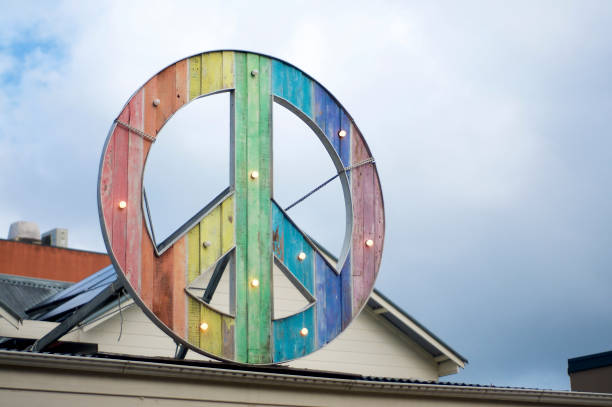 Rainbow colored peace sign Rainbow colored peace sign hanging on top of a building in Byron Bay woodstock stock pictures, royalty-free photos & images