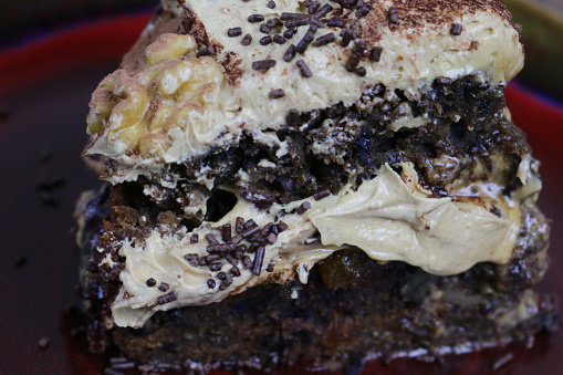 Stock photo showing a home made coffee cake topped with coffee flavoured butter cream, grated chocolate and decorated with walnut halves.