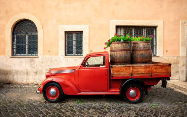 Old fashioned red car on Trastevere street in Rome, Italy.