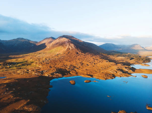 blue water and mountains in sunset light blue water and mountains in sunset light in ireland. view from drone connemara national park stock pictures, royalty-free photos & images